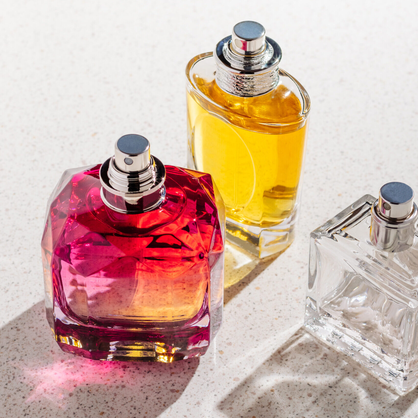 a group of perfume bottles on a white stone background on a sunny day